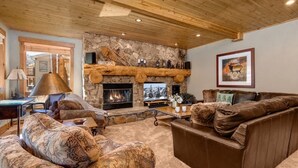 Un salón acogedor con chimenea de piedra, techo de madera y un sofá grande.