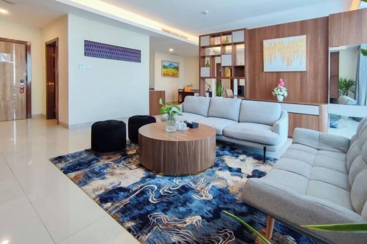 A modern living room with a sofa, a coffee table, and a patterned rug.