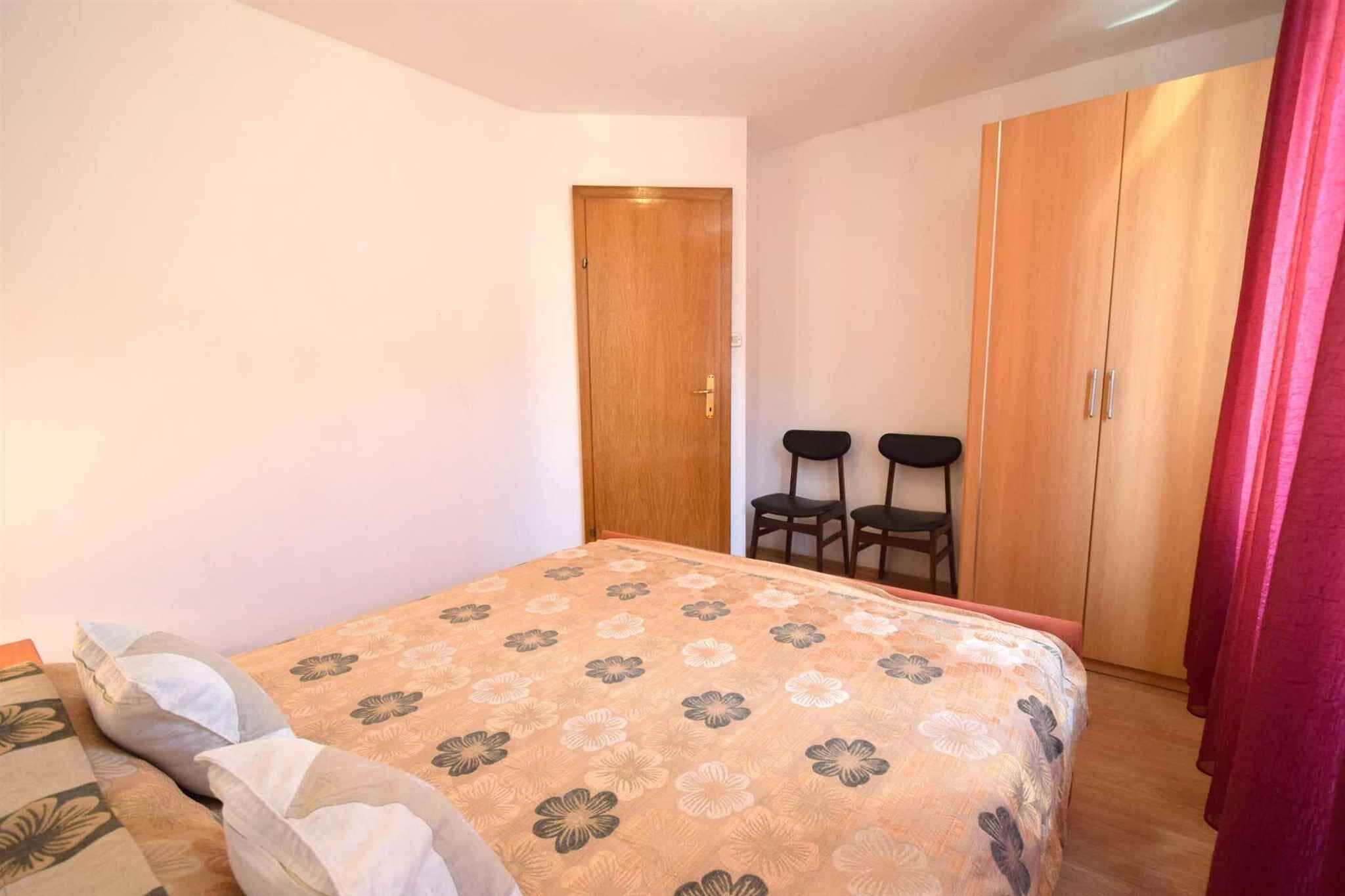 Une chambre à coucher avec un lit, une armoire et deux chaises.