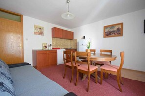 Una stanza compatta con un letto, un tavolo da pranzo con sedie, un angolo cottura e una lampada a parete.