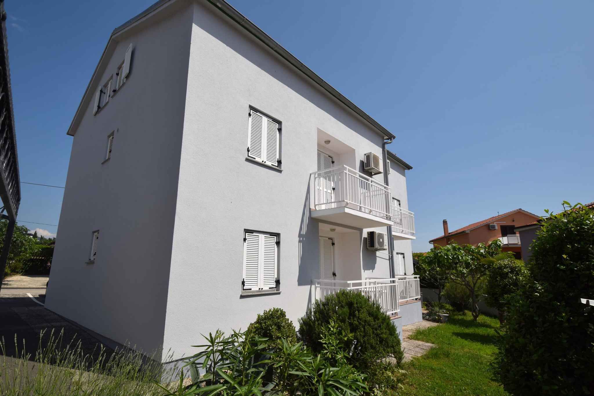 A two-story building with a balcony on the second floor, a small porch, and a garage door.