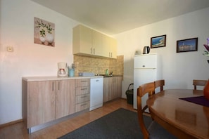 Una cocina compacta con armarios de madera, un lavavajillas blanco, una cafetera y un refrigerador.