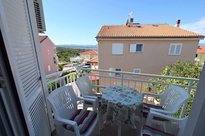A balcony with a table and chairs, overlooking a residential area with houses and a clear sky.
