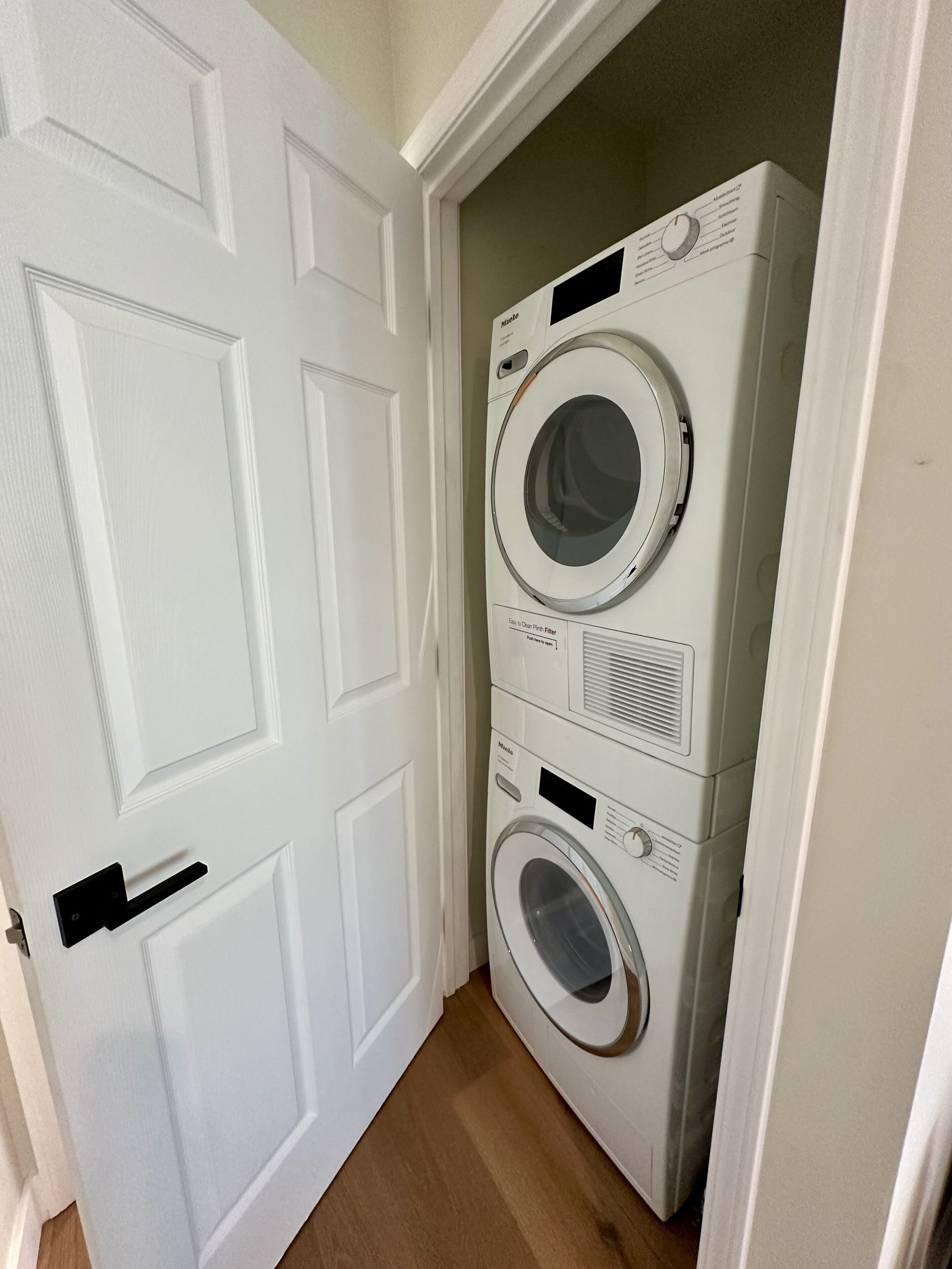 Une buanderie équipée d’un lave-linge et d’un sèche-linge à chargement frontal, installés l’un au-dessus de l’autre.