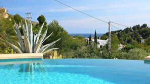 Une piscine d’un bleu éclatant, offrant une vue sur la mer et la végétation environnante.