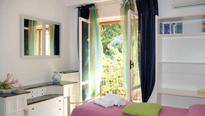A bedroom with two beds, a dresser, a mirror, and a window with curtains.