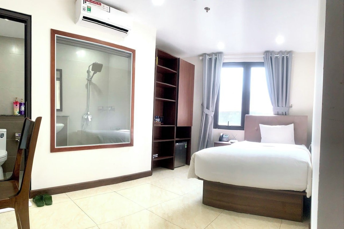 Een hotelkamer met een bed, een bureau, een stoel, een kledingkast en een badkamer met douche.