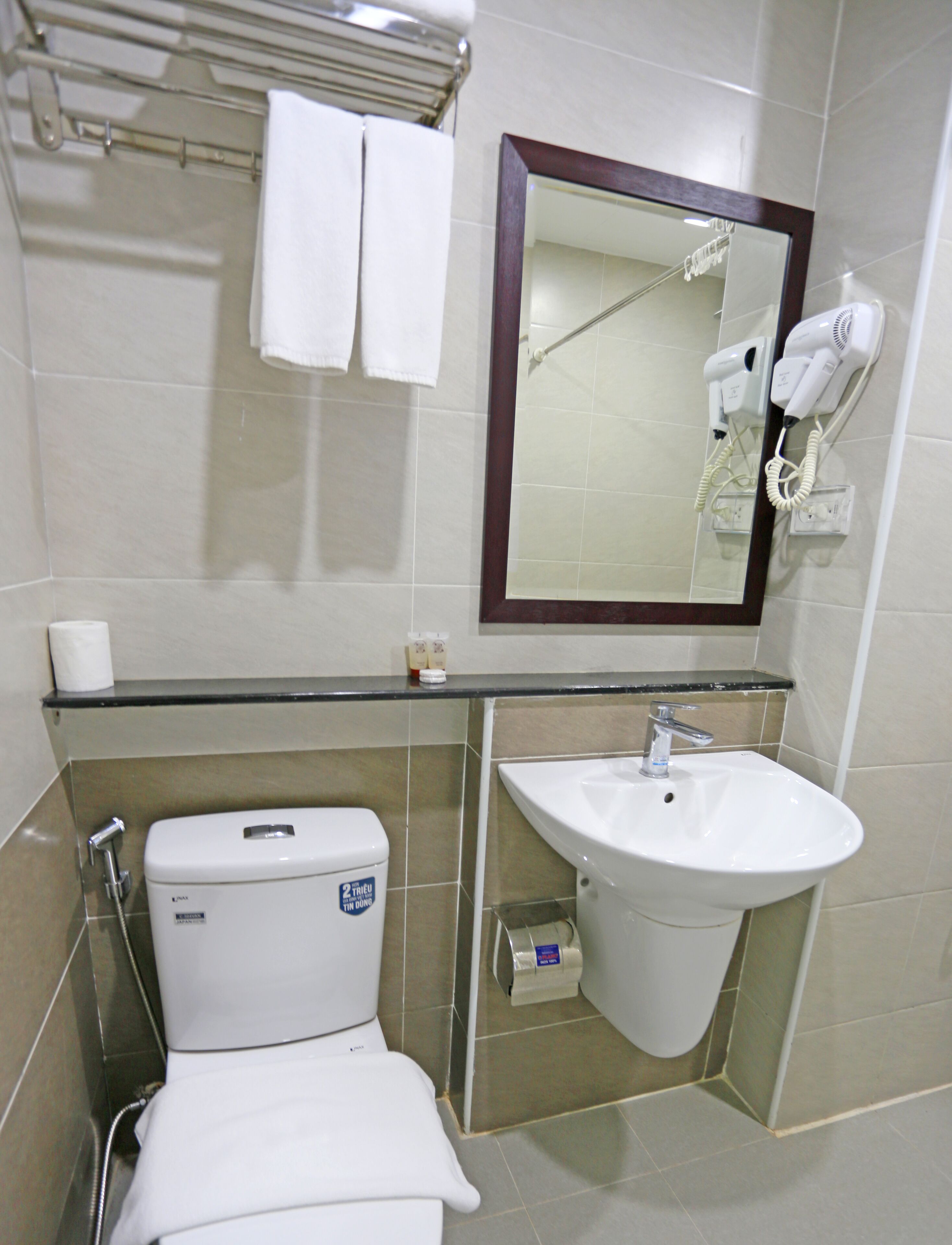 A bathroom with a toilet, sink, towel rack, and hair dryer.