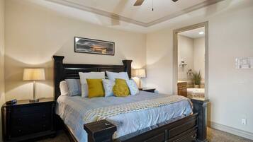 A bedroom with a bed, nightstands, a ceiling fan, a mirror, and a wall-mounted light fixture.