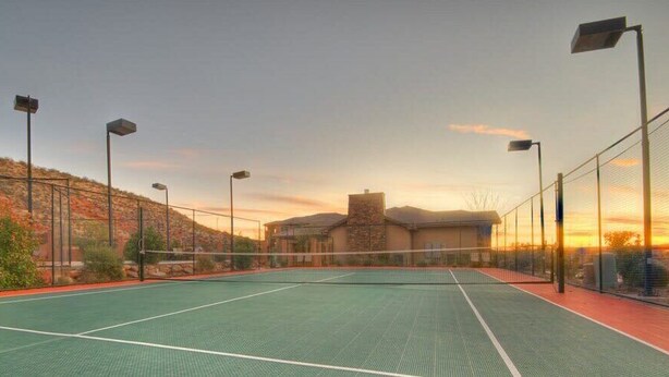 An outdoor tennis court with a net, surrounded by a fence, and street lamps. - Spacious 2-Bed Suite | Sunset Views, Private Patio & Fireplace (Hurricane)