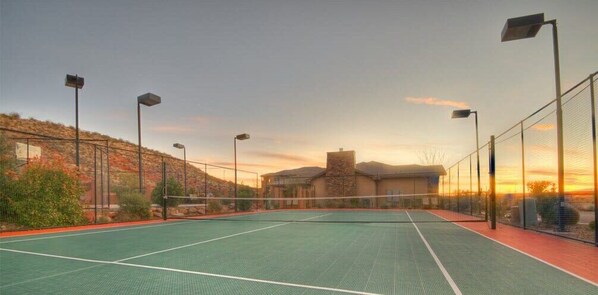 An outdoor tennis court with a net, surrounded by a fence, and street lamps. - Spacious 2-Bed Suite | Sunset Views, Private Patio & Fireplace (Hurricane)