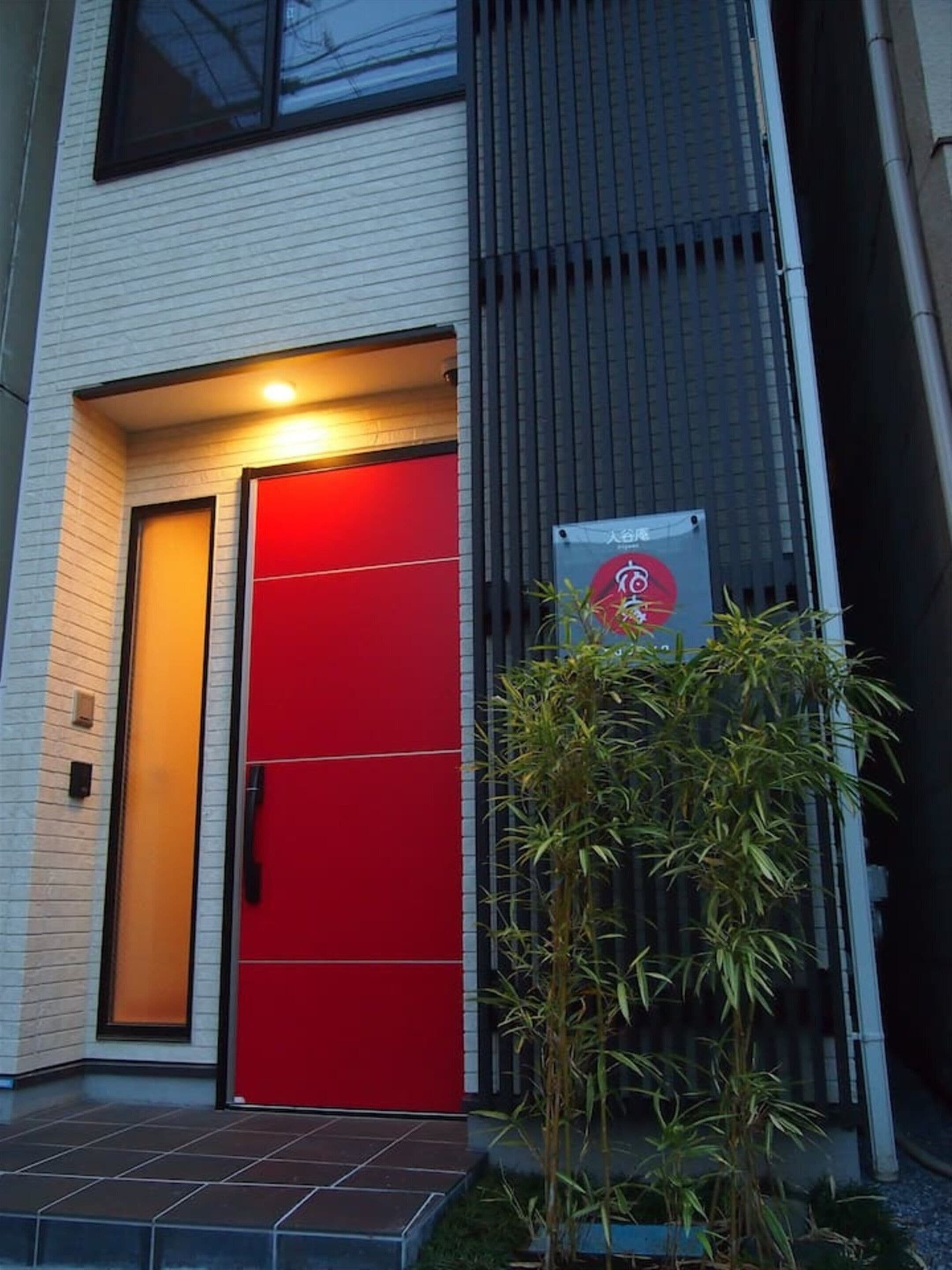 A modern building with a red door and a signboard.