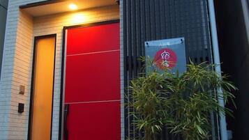 A modern building with a red door and a signboard.