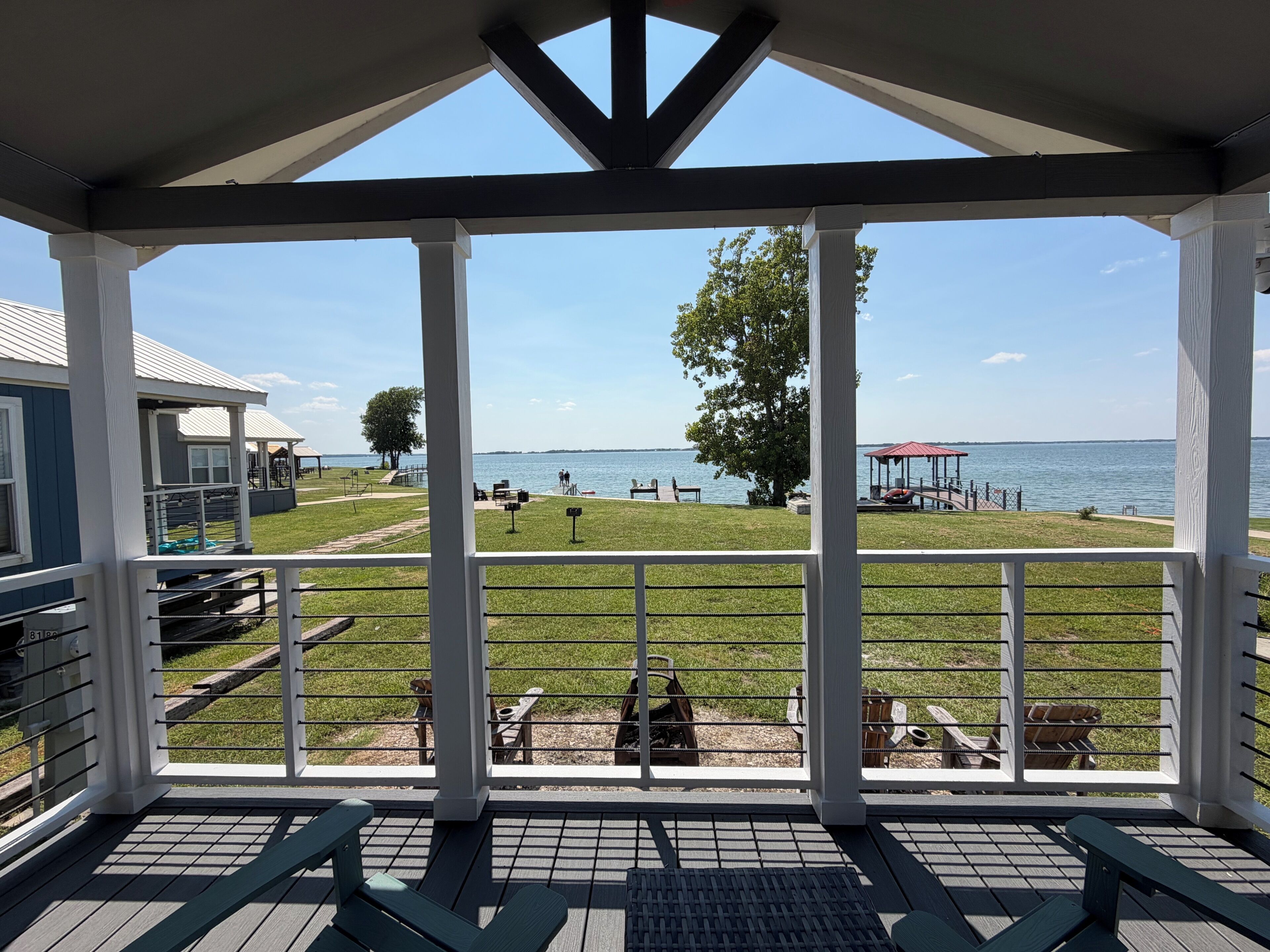 A covered deck with a view of a lake, outdoor seating, and a gazebo.