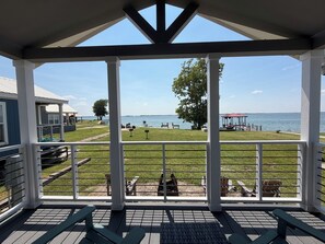 A covered deck with a view of a lake, outdoor seating, and a gazebo.