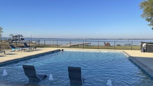 Una piscina con fuentes, sillas de descanso y vistas al mar.