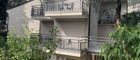 A multi-story building with balconies, a brick facade, and a large window.