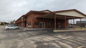 A two-story brick building with a covered parking area. - OKC Hotel (Oklahoma City)