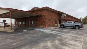 A brick building with a covered parking area and a parked pickup truck. - OKC Hotel (Oklahoma City)