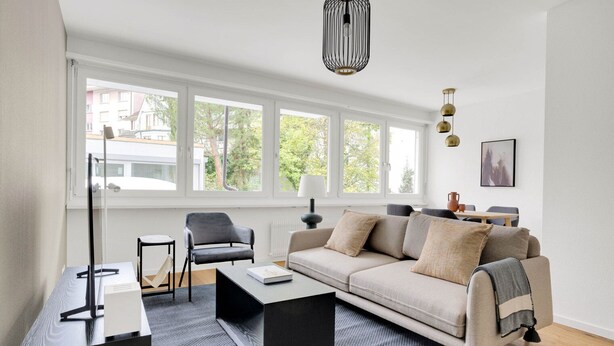 Un salon moderne comprenant un canapé, des fauteuils, une table basse et un téléviseur.