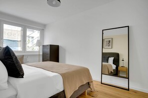 Une chambre à coucher avec un lit, une armoire, un miroir et une fenêtre.