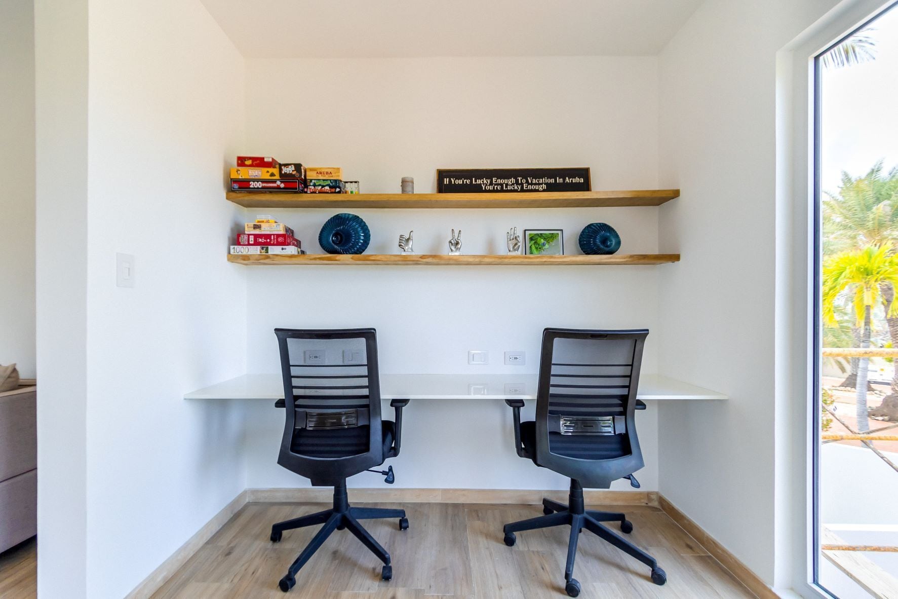 A workspace with two black office chairs, a white desk, and shelves with books and decorative items.