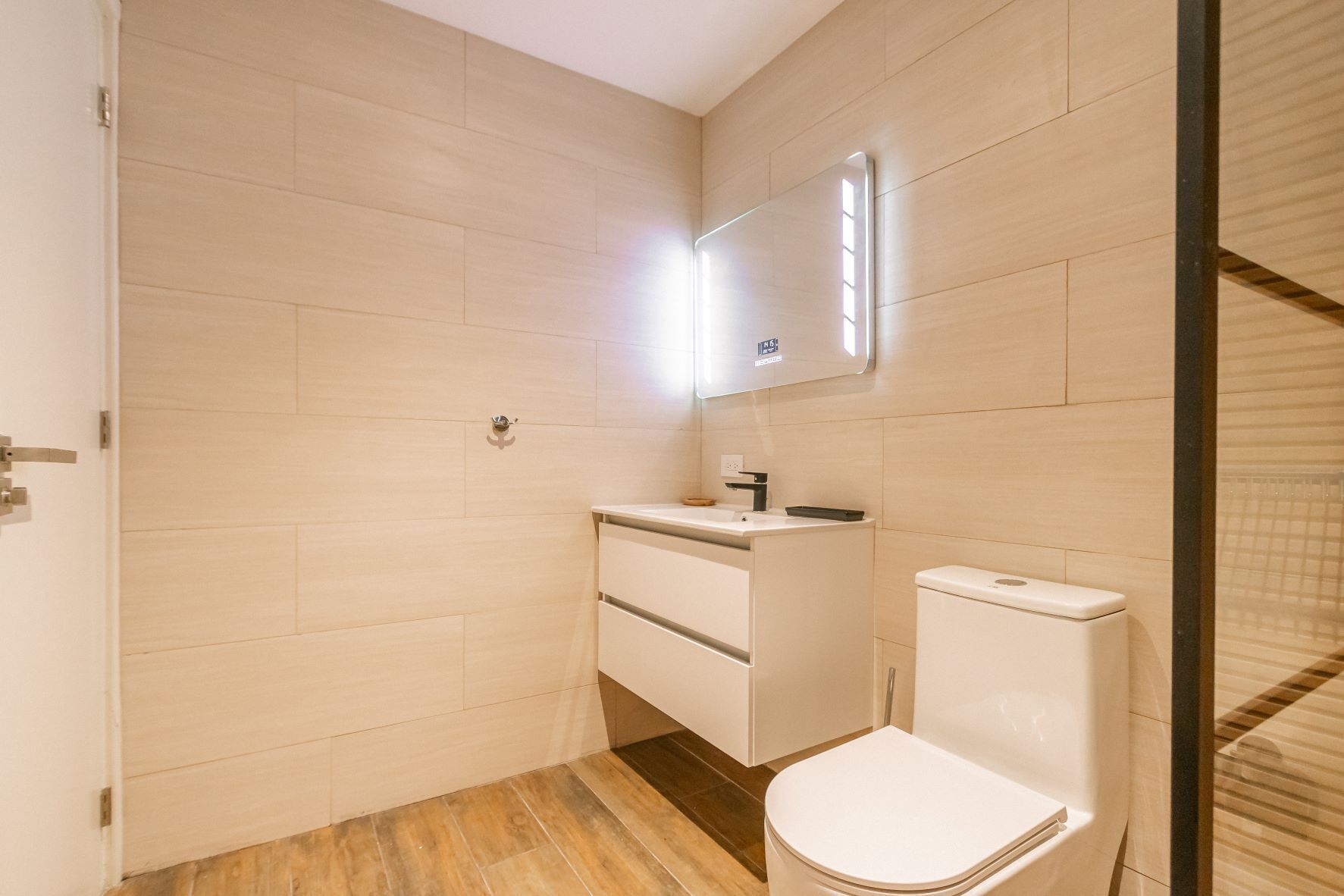 Ein modernes Badezimmer mit Toilette, Waschbecken und Spiegel.