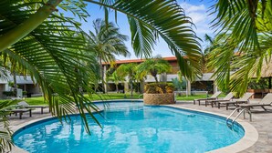 A swimming pool surrounded by palm trees and lounge chairs. - Jardines del Mar 3 (Oranjestad)