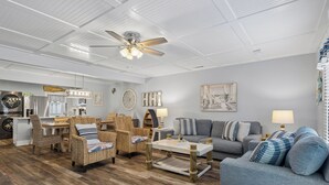 Un salon avec des meubles en osier, un ventilateur de plafond et un canapé gris.