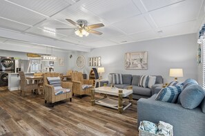 A living room with wicker furniture, a ceiling fan, and a grey sofa.