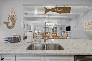 A kitchen with a marble countertop, a toaster, and a sink.
