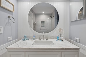 A bathroom with a marble sink, a large mirror, and a shower.