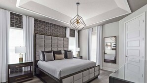 A modern bedroom with a large bed, a geometric-patterned headboard, a hanging light fixture, and a large mirror on the wall. - The Perfect Villa with a beautiful Private Pool, Orlando Villa 5601 (Orlando)