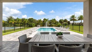 A pool area with a rectangular pool, lounge chairs, a table, and a fountain. - The Perfect Villa with a beautiful Private Pool, Orlando Villa 5601 (Orlando)