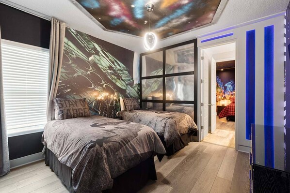 Un dormitorio con dos camas, un mural en la pared y un proyector de techo.