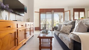Ein Wohnzimmer mit Holzschrank, Fernseher, Sofa und einem kleinen Tisch.