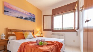 Ein Schlafzimmer mit Bett, Nachttisch, Fenster und einem Bild an der Wand.