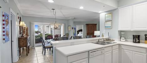 A spacious kitchen with white cabinetry, a large island with a sink, and a dining area with chairs and a table.