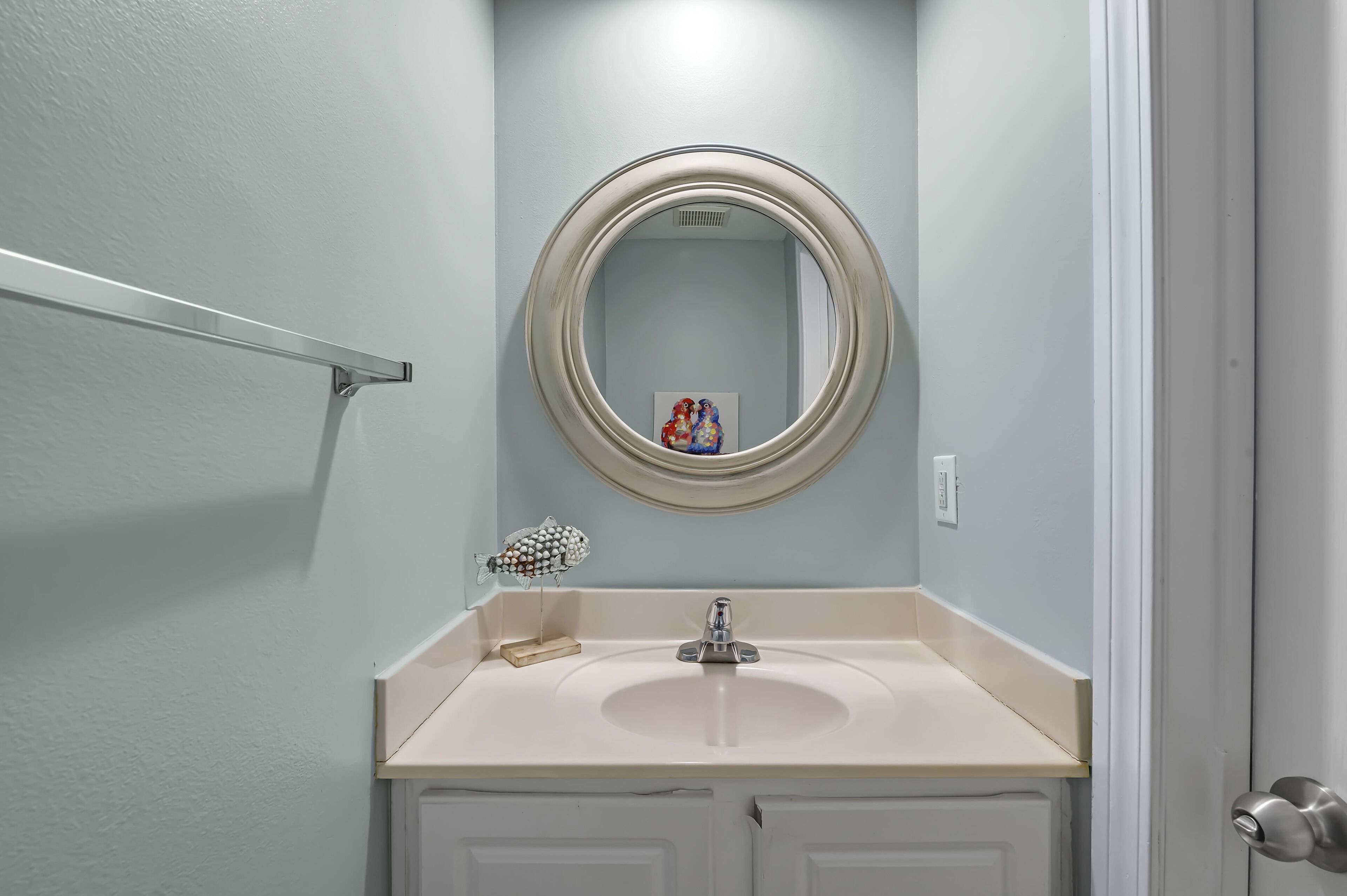 Een badkamer met een ronde spiegel, een wastafel en een handdoekhouder.