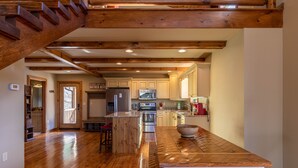 Une cuisine spacieuse avec des poutres en bois, un grand îlot central et des appareils électroménagers modernes.