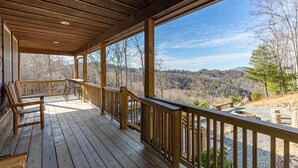 Une terrasse en bois, dotée de bancs et offrant une vue sur un paysage boisé.