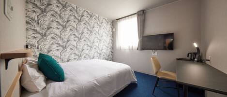 Une chambre d’hôtel avec un lit, un bureau, une chaise, une télévision et un papier peint à motifs.