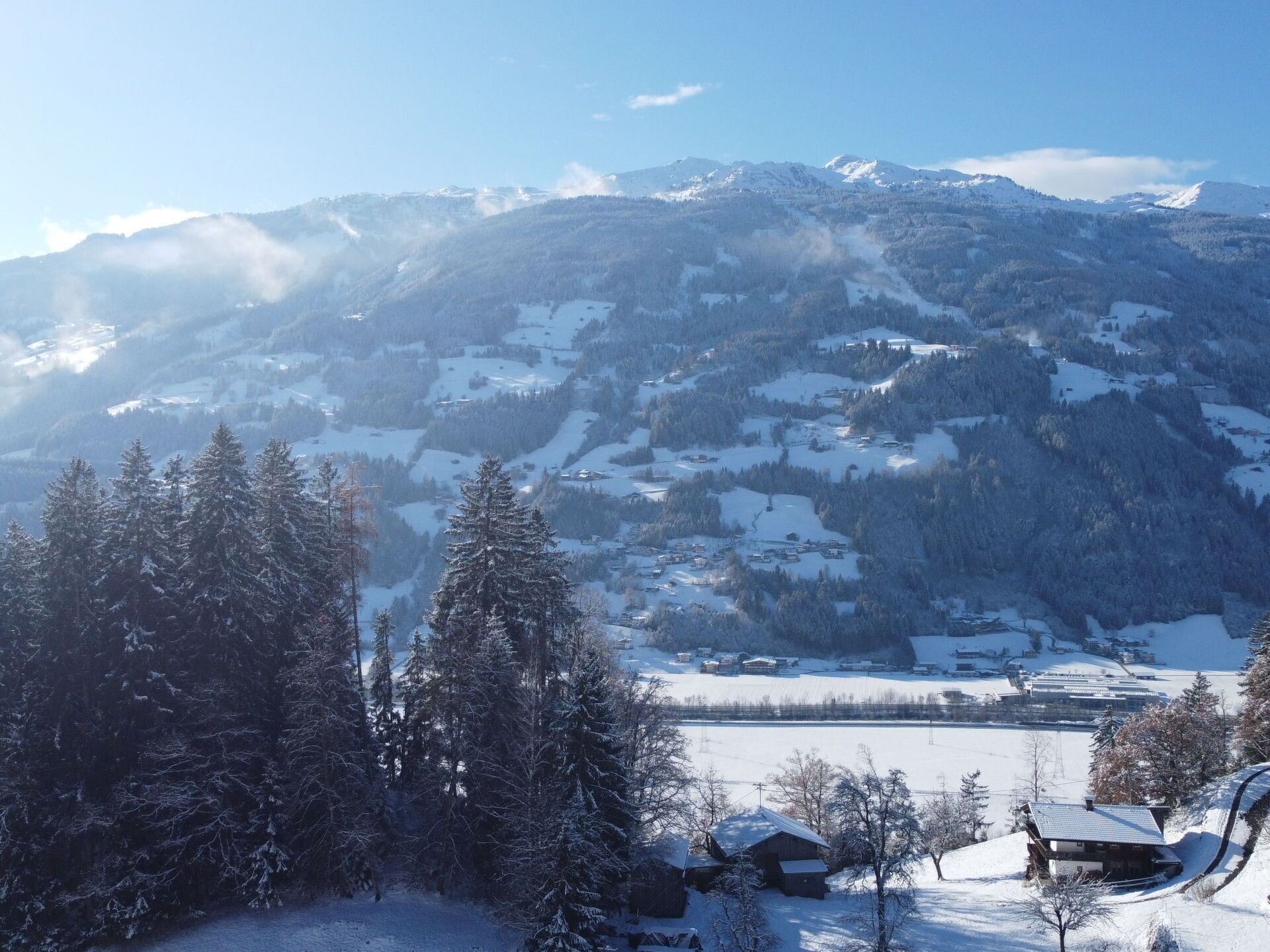 A mountainous landscape with snow-covered trees and buildings, likely a winter resort area.