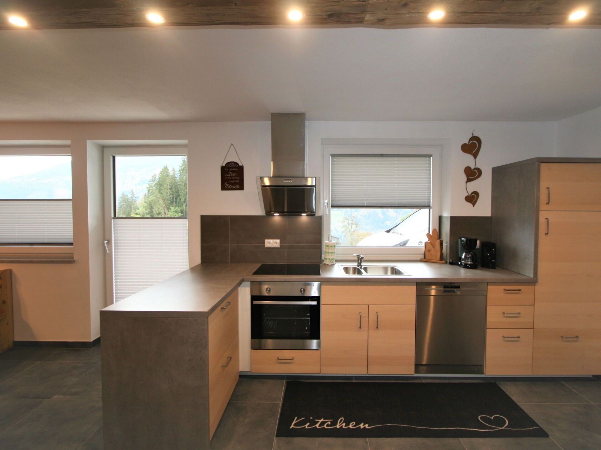 Eine moderne Küche mit integriertem Backofen, einer Edelstahl-Spüle und Holzschränken.