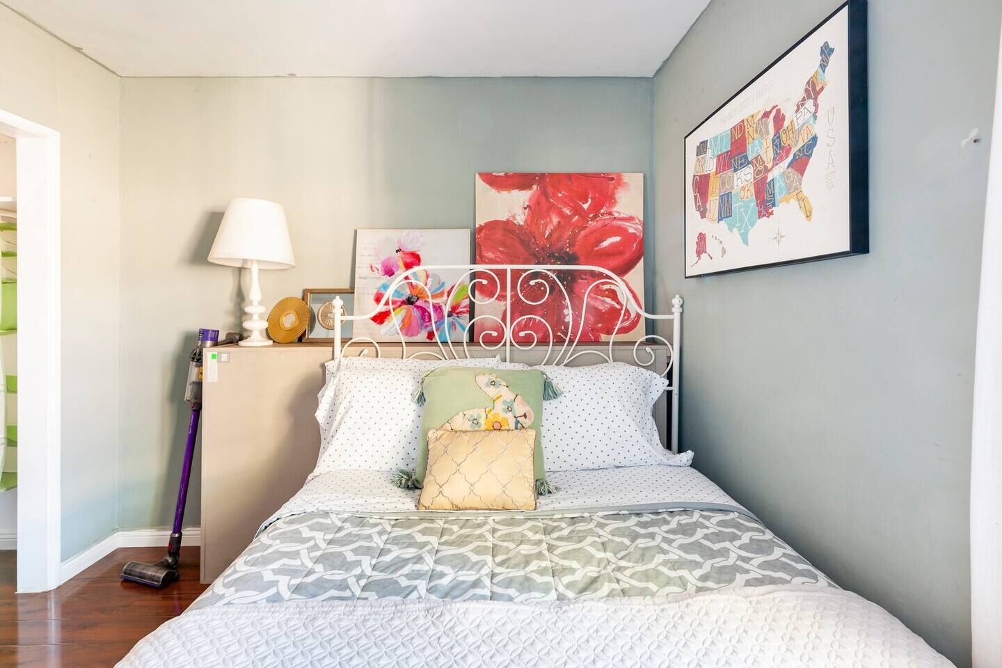 Un dormitorio con una cama, una mesita de noche, una lámpara y dos cuadros en la pared.