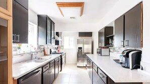 A modern kitchen with stainless steel appliances, black cabinets, and a white countertop. - Amazing & Relaxing 5B3B-Private Pool (Monrovia)