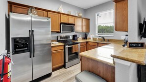 A modern kitchen with stainless steel appliances, wooden cabinets, granite countertops, and a built-in oven.
