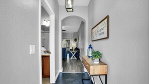 A hallway with a wooden console table, a framed welcome sign, and a potted plant.