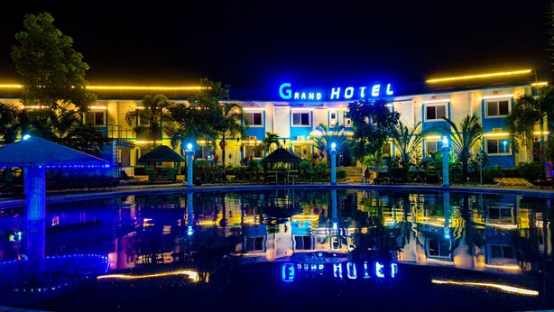 Un grand hôtel doté d’une piscine qui reflète ses lumières et d’une façade bien éclairée.