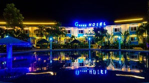 Un Gran Hotel con una piscina que refleja sus luces y una fachada bien iluminada.